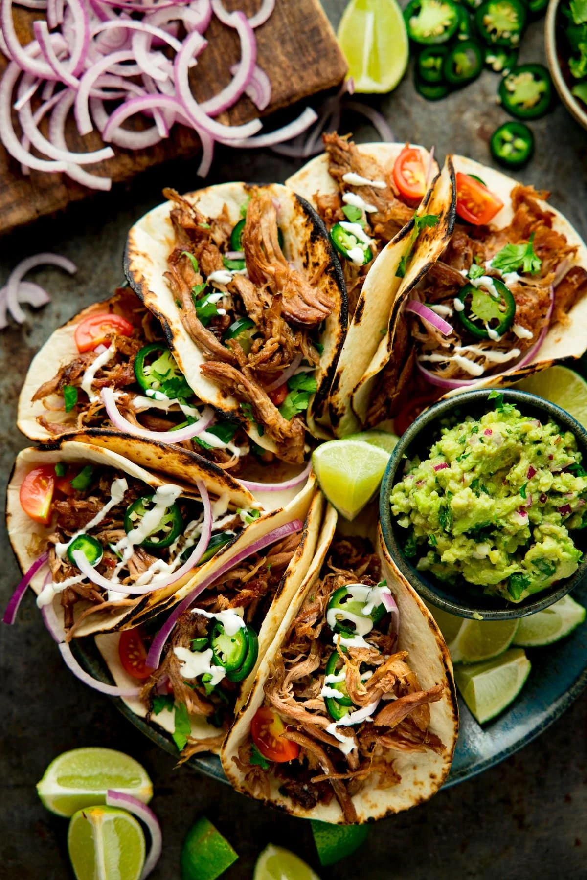 Overhead shot of Lamb Barbacoa Carnitas Tacos on a plate with a bowl of guacamole